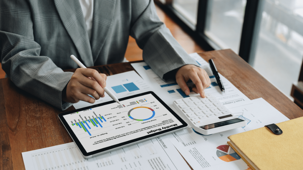 Business professional analyzing inventory charts on tablet with calculator