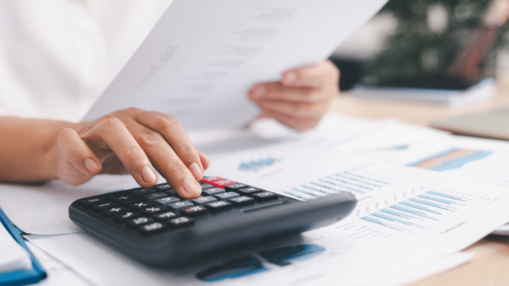 Calculator and financial reports used for inventory cost analysis and seasonal planning decisions