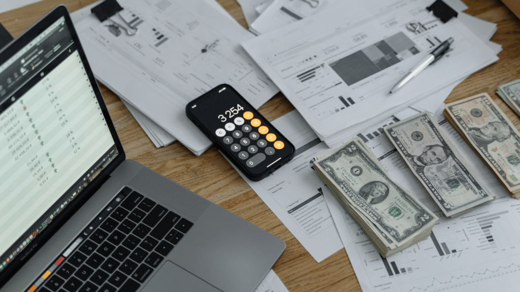Business financial documents, calculator, cash and laptop illustrating Profit First cash management.
